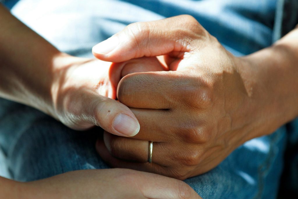 A carer holding a patient's hand.