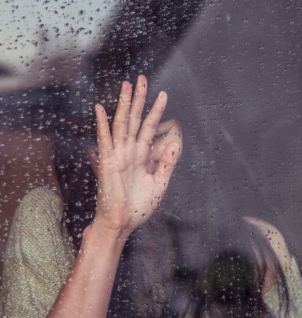 Emotional woman with her hand on a window.